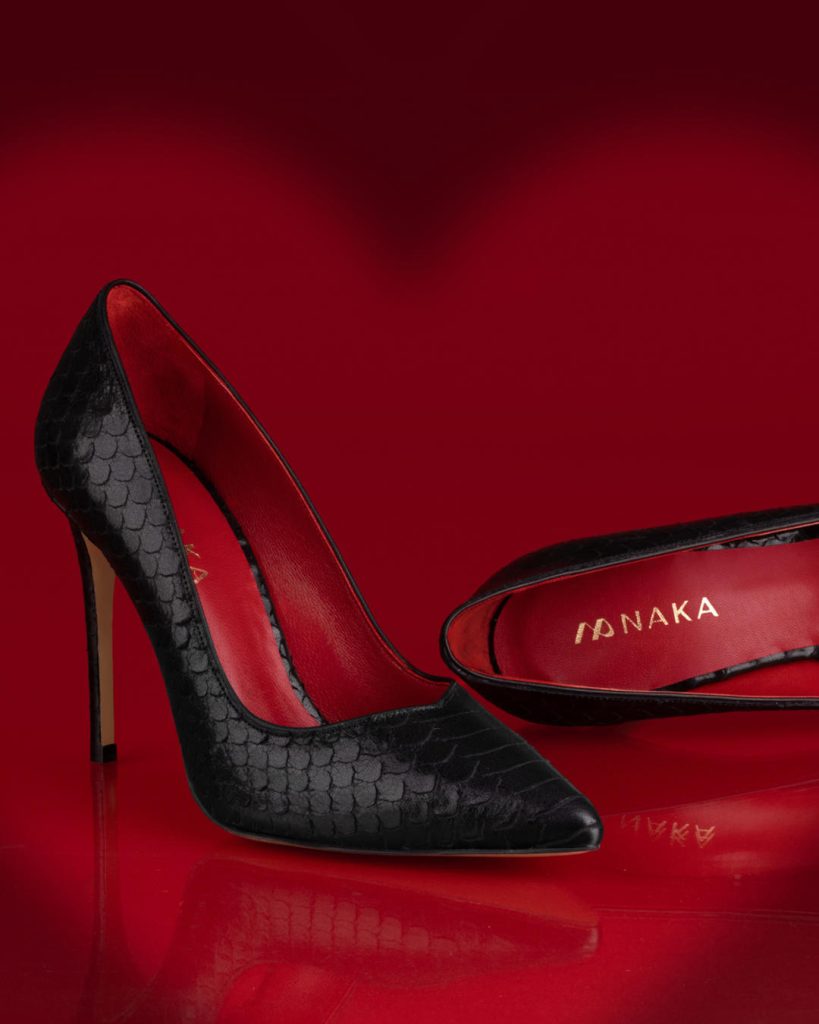 Proslavite naš dan u koraku koji osvaja svet! - Ženske salonke na akciji 1 Dark Pleasure su zenske kozne cipele sa zmijskim dezenom spolja, crne boje, a unutra upadljivo crvene boje. Na ovoj slici se nalaze naspravm crvene pozadine.