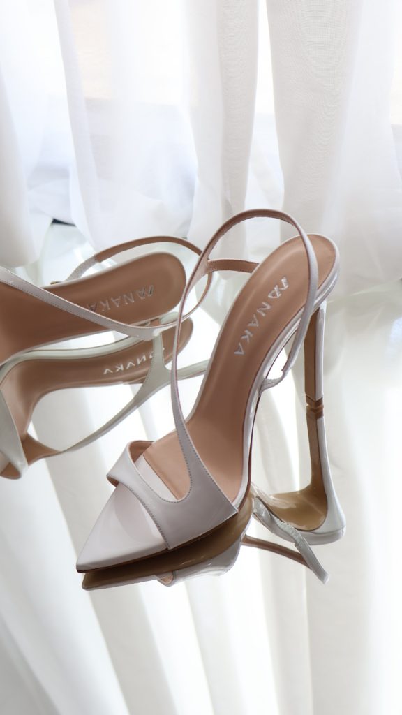 Zenske sandale na stiklu White Glow. Bele boje, sa kaišem, otvorenih prstiju, lakovane i sa visokom štiklom.